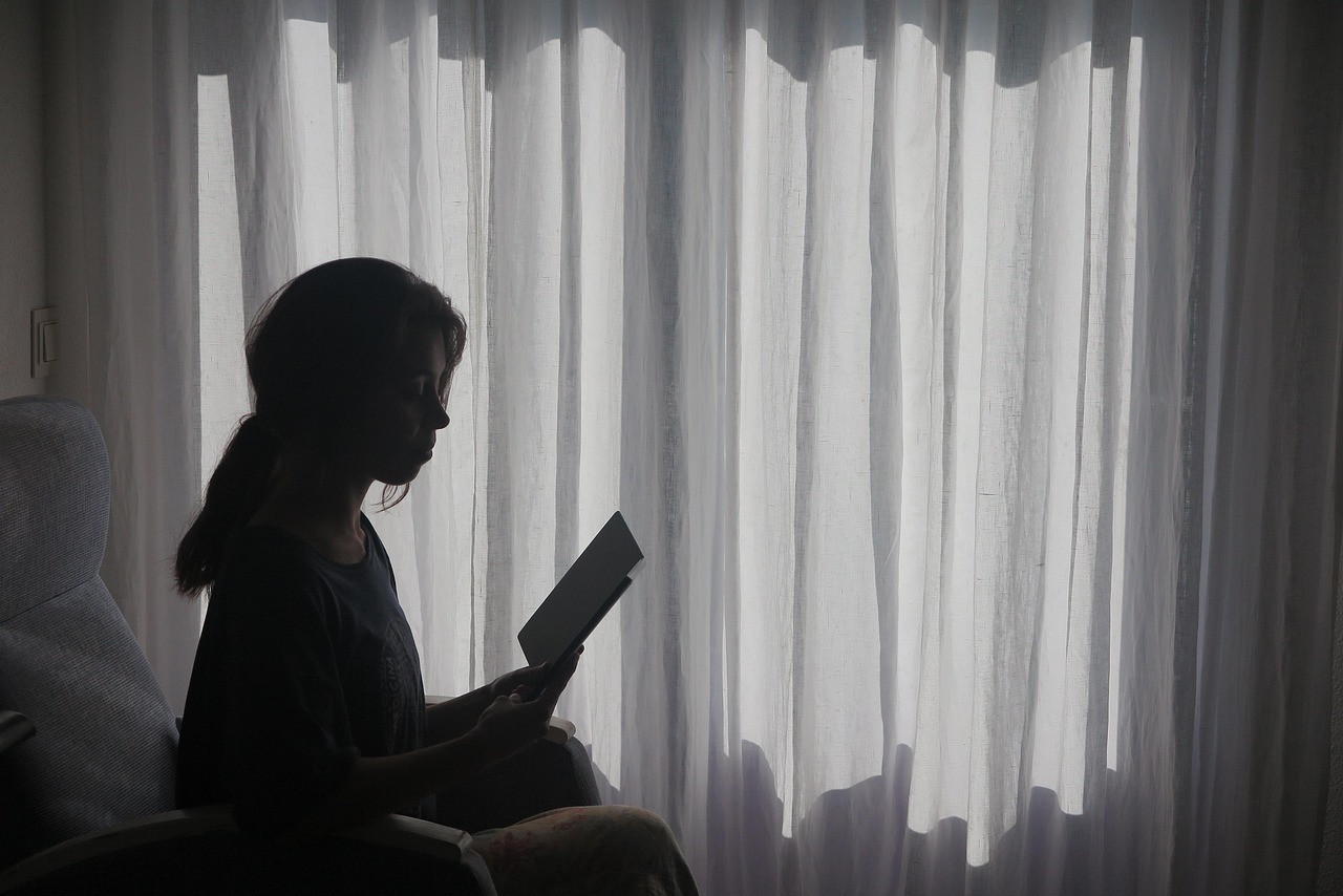Representative image: woman sitting by window thinking