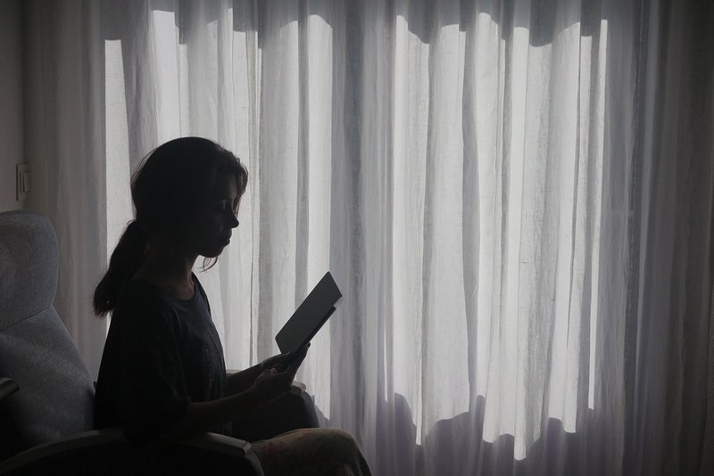 Representative image: woman sitting by window thinking